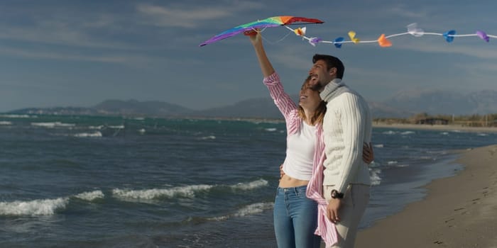 Loving Couple Flying A Kite at Beach and having fun on autumn day