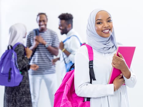 portrait of young african modern muslim female student with group of friends in background  wearing traditional Islamic hijab clothes