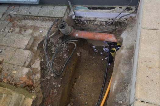 Work on the installation of engineering and heating systems. Two plastic pipes one yellow for gas pipe and one black for power lines. They are in a sand ditch.