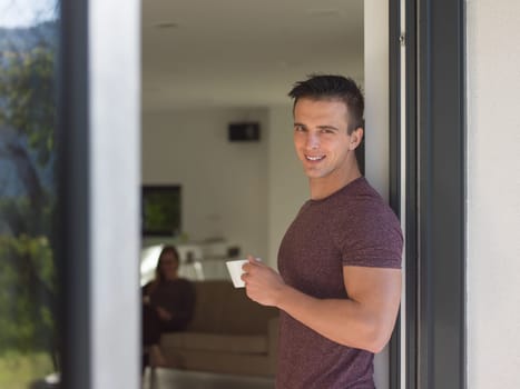 portrait of a young successful man drinking coffee in the doorway of his luxury home villa