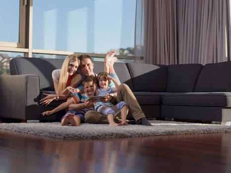 Happy Young Family Playing Together with tablet at home sitting on the sofa