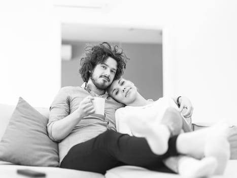 Young couple on the sofa watching television together in their luxury home
