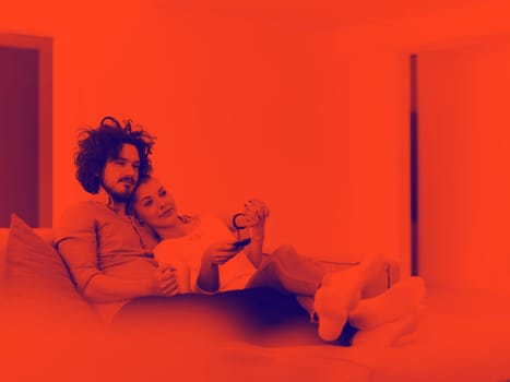 Young couple on the sofa watching television together in their luxury home
