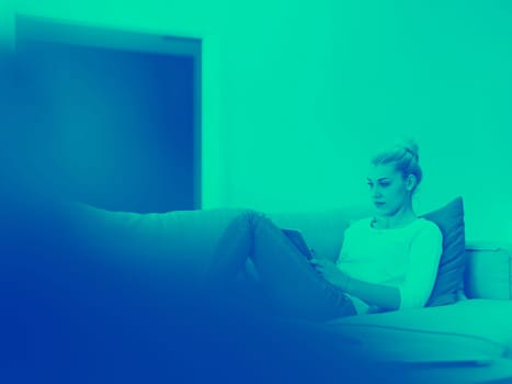 young happy woman on sofa using tablet computer at luxury home