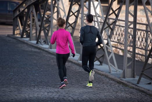 healthy young  couple jogging in the city  at early morning with sunrise in background