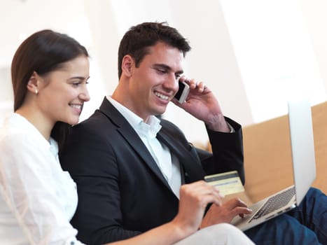 happy young relaxed  couple working on laptop computer at modern home interior