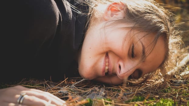 Toned portrait of beautiful smiling woman lying in forest and listening the ground. Concept of ecology, environment protection and harmony with nature.