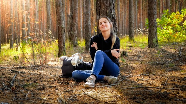 Beautiful female tourist resting on the ground in forest after lng journey on the hiking route.