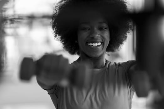 happy healthy african american woman working out in a crossfit gym on weight loss with dumbbells