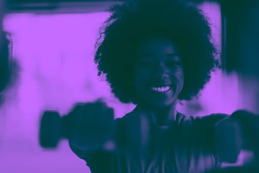 happy healthy african american woman working out in a crossfit gym on weight loss with dumbbells duo tone filter