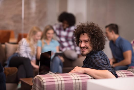 Portrait of smiling young informal businessman with colleagues in background at the office