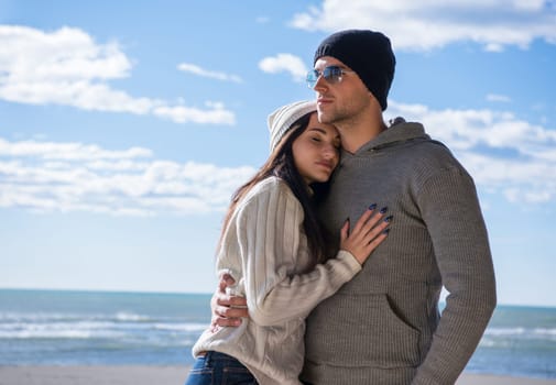 Happy couple enyojing time together on beach during autumn day