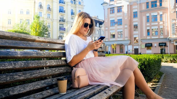Beautiful sexy woman sitting on bench and using smartphone.