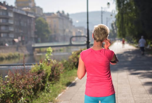 jogging woman setting music and running route on  smart phone putting  earphones before morning run