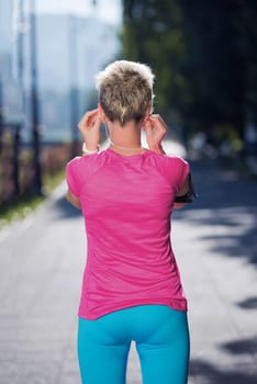 jogging woman setting music and running route on  smart phone putting  earphones before morning run