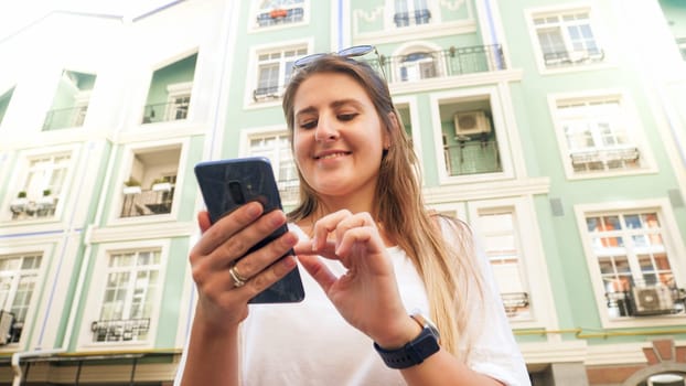 Portrait of happy young girl with smartphone typing message in social medi on smartphone.