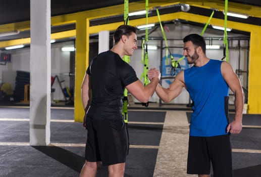 a young men athletes making high five after hard exercise at cross fitness gym