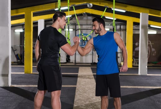 a young men athletes making high five after hard exercise at cross fitness gym
