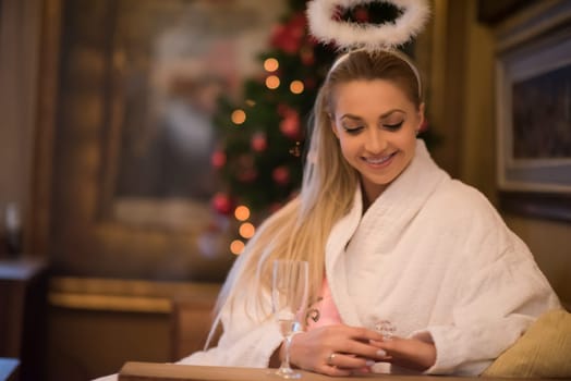 people, and relaxation concept   beautiful young woman in bath robe drinking champagne at spa over holidays lights background
