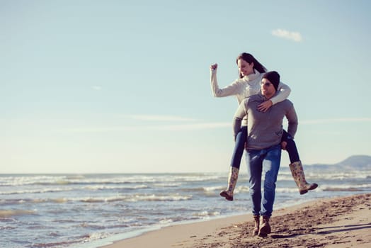 Men Giving Piggy Back Rides his girlfriend At Sunset By The Sea, autumn time