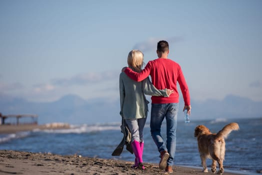 Couple Running On The Beach Holding Their Hands with dog On autmun day