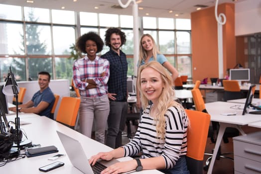 young smiling informal businesswoman working in the office with colleagues in the background