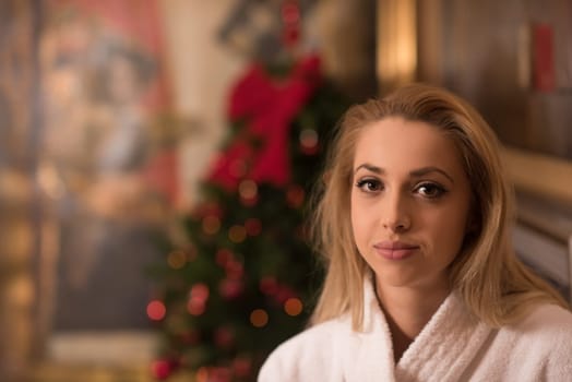 people, and relaxation concept   beautiful young woman in bath robe drinking champagne at spa over holidays lights background