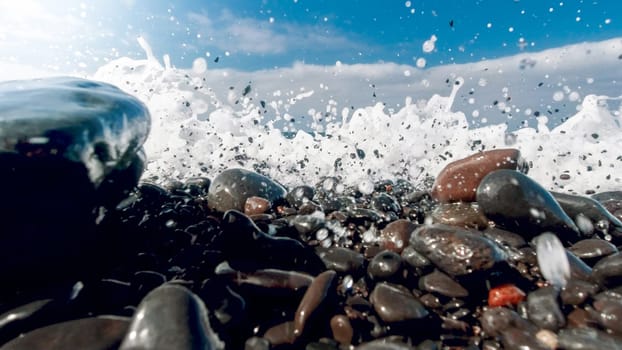 Closeup image of powerful ocean waves breaking and rolling tones and rocks on the sea beach.