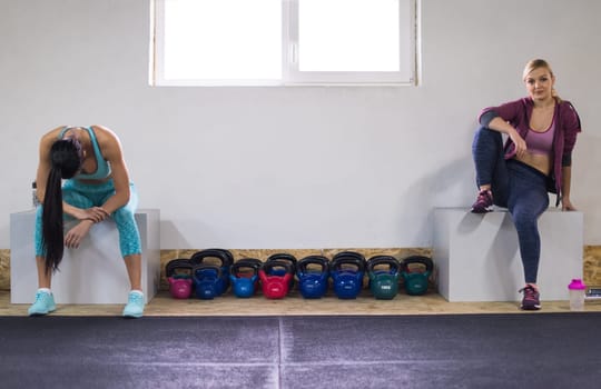 young athletes women sitting relaxing after exercise at cross fitness gym