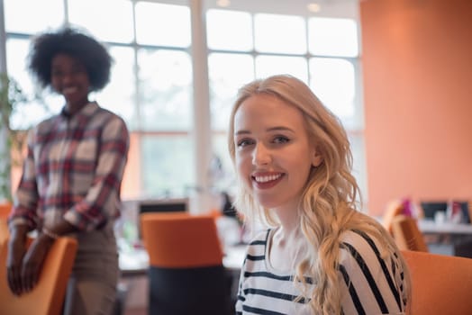 young smiling informal businesswoman working in the office with colleagues in the background