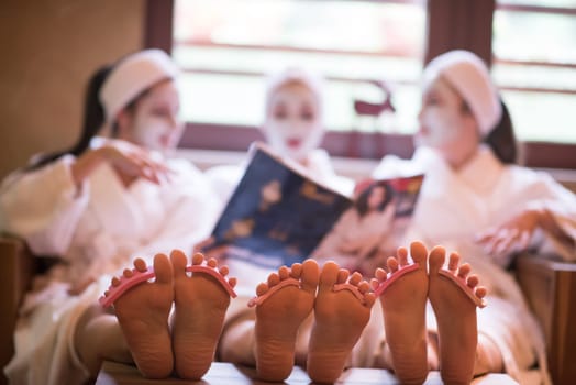 group of famale friends in spa have fun, celebrate bachelorette party with face mask