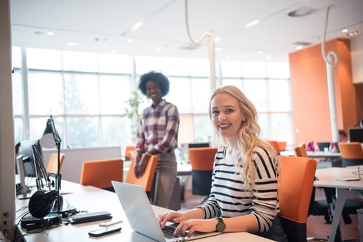 young smiling informal businesswoman working in the office with colleagues in the background
