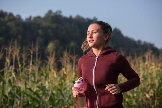 young woman enjoying in a healthy lifestyle while jogging along a country road, exercise and fitness concept