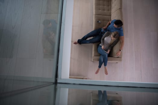 Young couple sitting on a sofa in the luxury living room, using a tablet computer top view