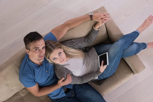 Young couple sitting on a sofa in the luxury living room, using a tablet computer top view