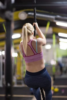 young muscular woman doing rope climbing in cross fitness gym