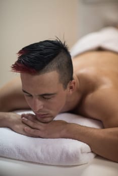attractive handsome man resting in a spa massage center, lying on table relaxing closed eyes  concept of men beauty health care