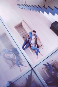 Young couple sitting on a sofa in the luxury living room, using a tablet computer top view