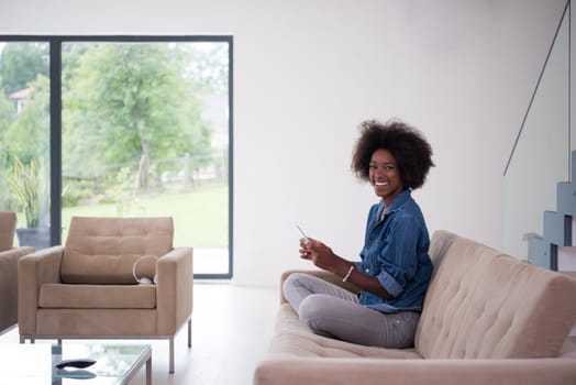 Young african american woman at home relaxing in her luxury lliving room reading a digital tablet PC surf internet and work