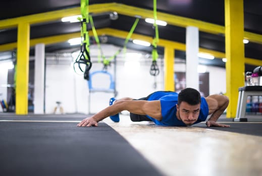 Young strong man doing pushups  at cross fitness gym