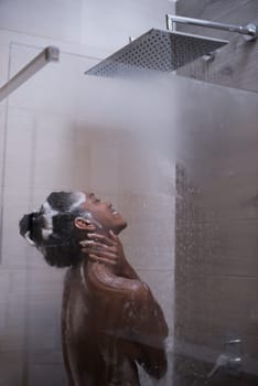 Woman in the shower,beautiful black young female showering under refreshing water, healthy lifestyle, enjoying time in luxury spa resort