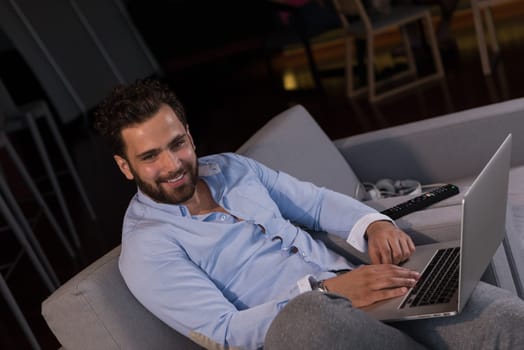 technology, home and lifestyle concept  of man working from home using laptop computer and sitting on sofa