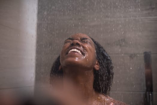 Woman in the shower,beautiful black young female showering under refreshing water, healthy lifestyle, enjoying time in luxury spa resort