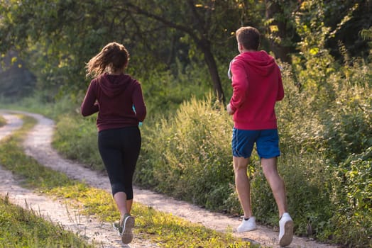 young couple enjoying in a healthy lifestyle while jogging along a country road, exercise and fitness concept