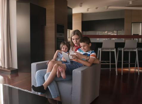 happy Mother spending time with kids using tablet computer on an armchair  at home
