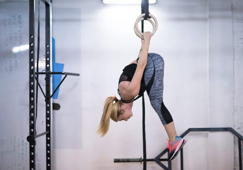 young athletic woman working out on gymnastic rings at the cross fitness gym