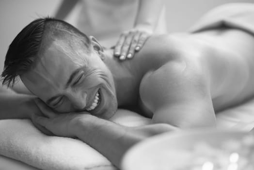 Positive young man having a back massage in a spa center