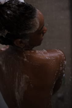 Woman in the shower,beautiful black young female showering under refreshing water, healthy lifestyle, enjoying time in luxury spa resort