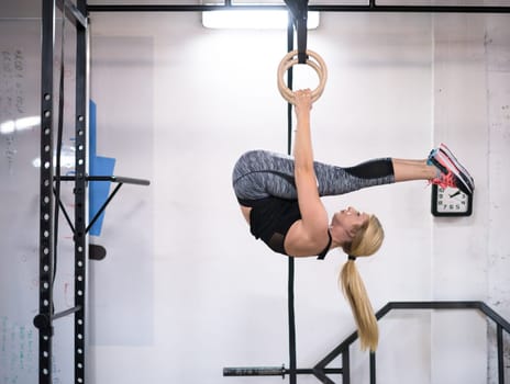 young athletic woman working out on gymnastic rings at the cross fitness gym