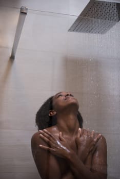 Woman in the shower,beautiful black young female showering under refreshing water, healthy lifestyle, enjoying time in luxury spa resort